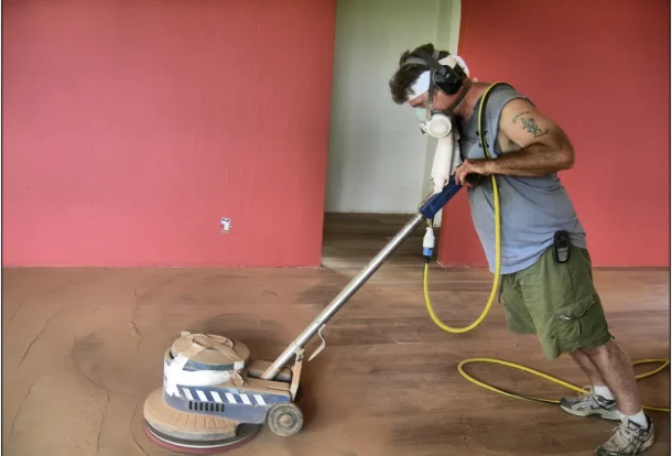 Person cleaning a carpet in a living room with a stone fireplace, using a carpet cleaner.