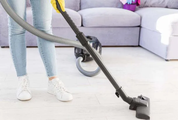 Person vacuuming near a sofa – highlighting Advantages of Surface Buffing