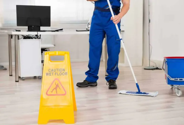 Person cleaning a carpet in a living room with a stone fireplace, using a carpet cleaner.