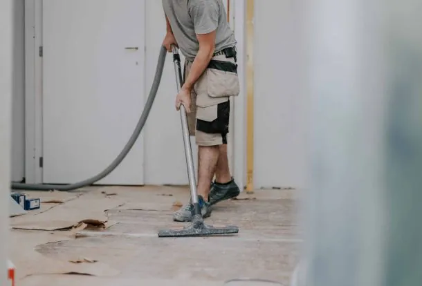 post construction cleaning a carpet in a living room with a stone fireplace, using a carpet cleaner.