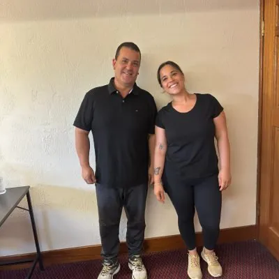 Two professional cleaners representing a cleaning company, dressed in casual black uniforms, smiling and ready to provide expert cleaning services