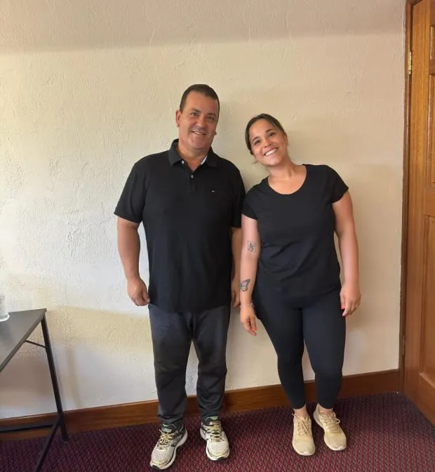 Two professional cleaners representing a cleaning company, dressed in casual black uniforms, smiling and ready to provide expert cleaning services